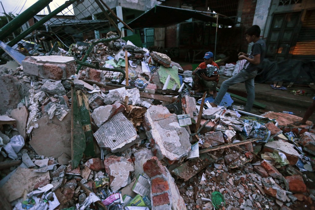 People stand amongst the rubble of fallen homes in Manta on April 17, 2016, after a powerful 7.8-magnitude earthquake struck Ecuador on April 16.  At least 77 people were killed when a powerful 7.8-magnitude earthquake struck Ecuador, destroying buildings and a bridge and sending terrified residents scrambling from their homes, authorities in the Latin American country said on April 17. / AFP PHOTO / JUAN CEVALLOS