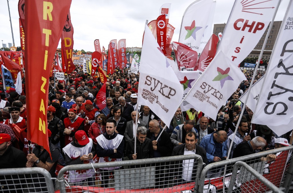 People wave flags as they gather for a May Day rally in Bakirkoy, a district of Istanbul, on May 1, 2016. Turkish police on clamped down on unauthorised protests during a tense May Day in Istanbul, using tear gas and water cannon against demonstrators and imposing a heavy security blanket on the city. / AFP PHOTO / BULENT KILIC