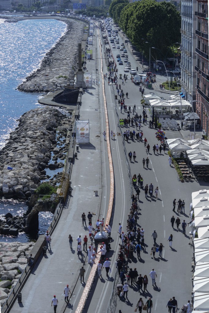 Neapolitan pizza makers attempt to make the longest pizza to break a Guinness World Record along the seafront of Naples, on May 18, 2016. For the wood-fired pizza, which measured two kilometres, they used 2,000 kg of flour, 1,600 kg of tomatoes, 2,000 kg of mozzarella, 200 litres of oil, 30kg of fresh basil. The record-breaking snack measured up at exactly 1,853.88 metres (6,082 feet), smashing the previous record of 1,595.45 metres (5,234 feet) set at last year's World Expo in Milan, Italy's food and agriculture board Coldiretti said. / AFP PHOTO / Mario LAPORTA
