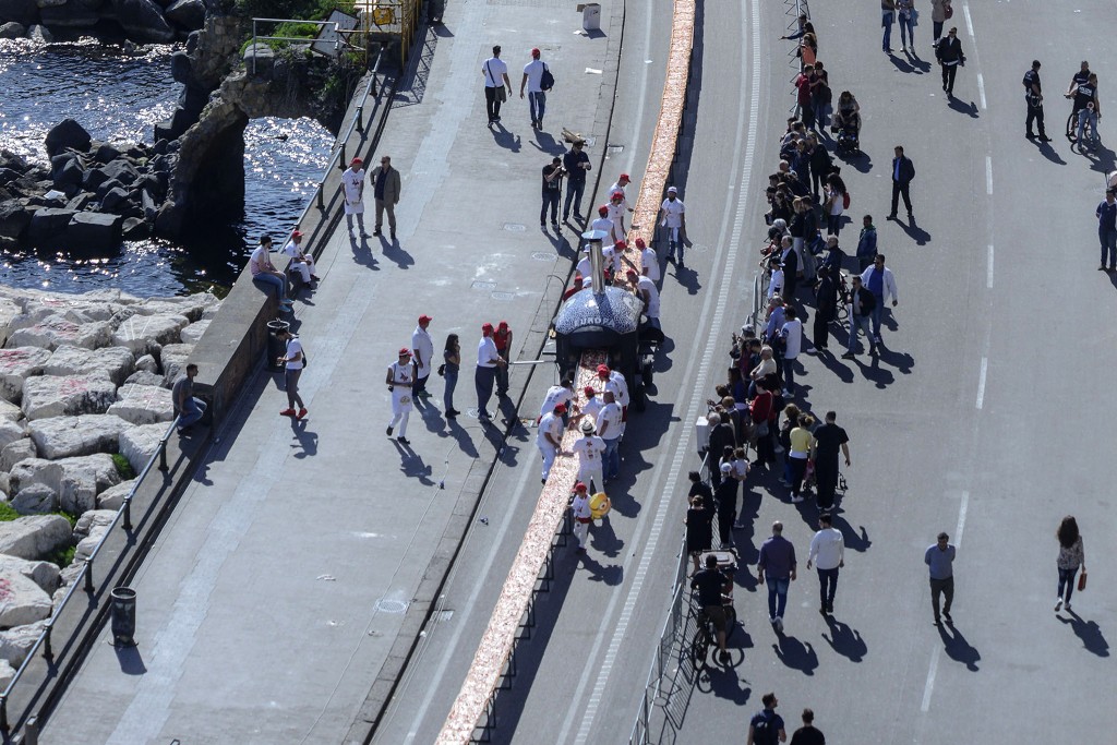 Neapolitan pizza makers attempt to make the longest pizza to break a Guinness World Record along the seafront of Naples, on May 18, 2016. For the wood-fired pizza, which measured two kilometres, they used 2,000 kg of flour, 1,600 kg of tomatoes, 2,000 kg of mozzarella, 200 litres of oil, 30kg of fresh basil. The record-breaking snack measured up at exactly 1,853.88 metres (6,082 feet), smashing the previous record of 1,595.45 metres (5,234 feet) set at last year's World Expo in Milan, Italy's food and agriculture board Coldiretti said. / AFP PHOTO / Mario LAPORTA