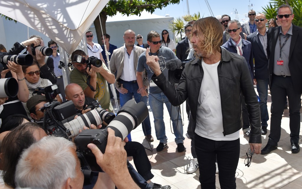 US singer Iggy Pop gives the fingers while posing on May 19, 2016 during a photocall for the film "Gimme Danger" at the 69th Cannes Film Festival in Cannes, southern France. / AFP PHOTO / LOIC VENANCE