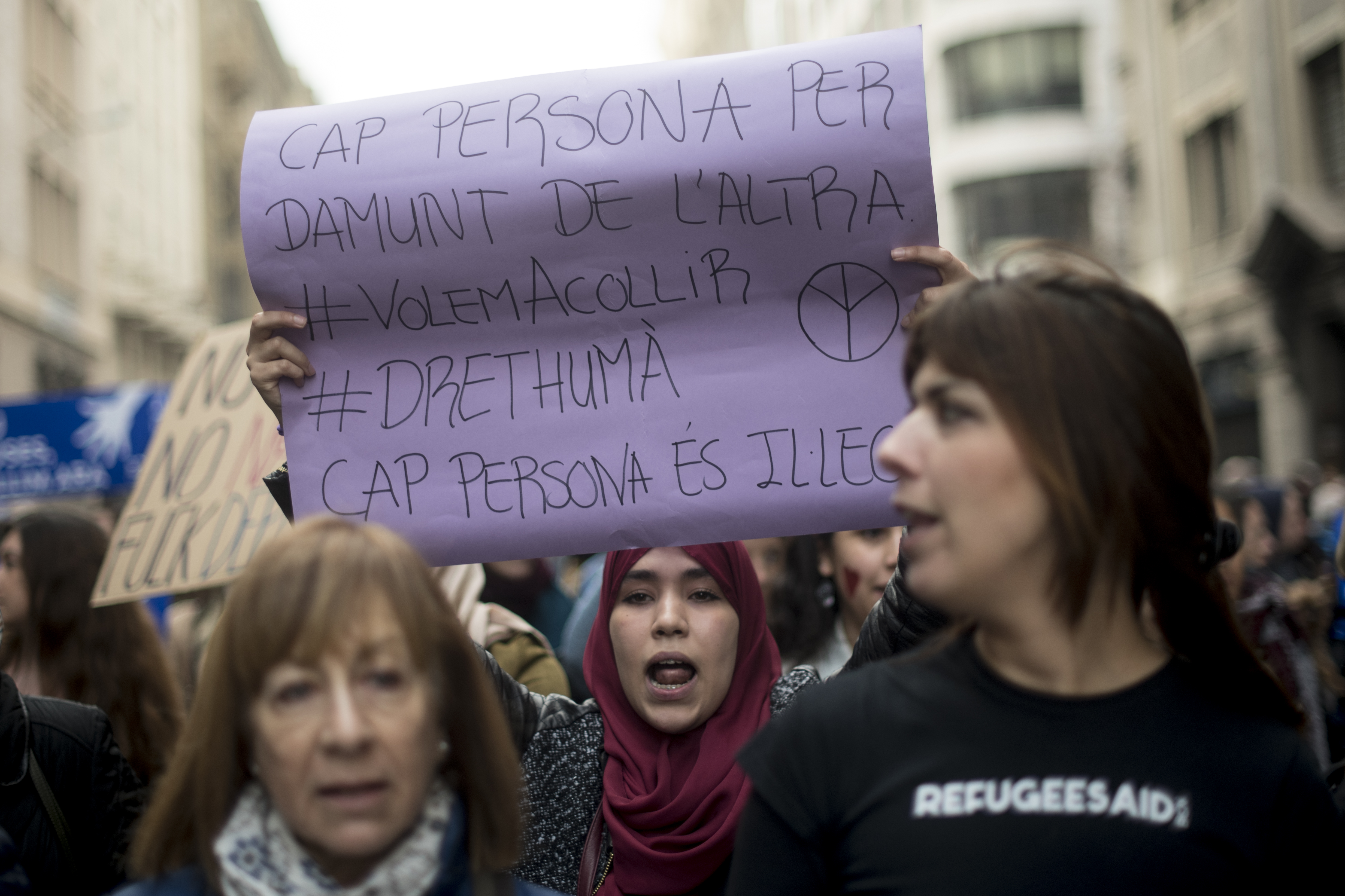 A woman holds a placard reading "No one is above another, No one is illegal" during a demonstration to demand to welcome refugees in Barcelona on February 18, 2017.  Some 160,000 people participated today in a demonstration in Barcelona to demand that Spain welcomes "right now" thousands of refugees as it had committed itself in 2015. / AFP PHOTO / Josep Lago