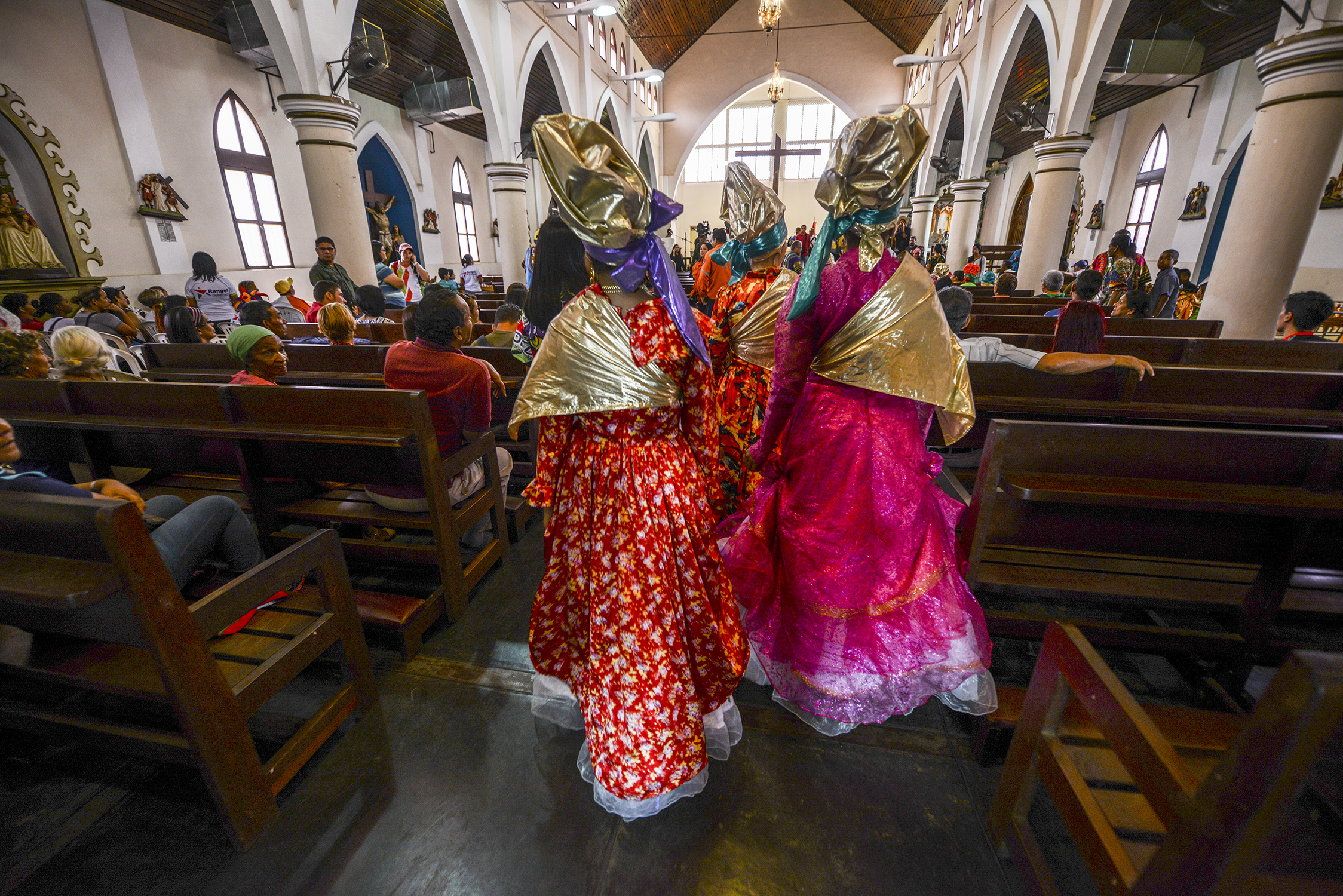 Women dressed as "madamas" attend a mass before the beginning of the Carnival in El Callao, Bolivar state, Venezuela on February 26, 2017.  El Callao's carnival was recently named Unesco's Intangible Cultural Heritage of Humanity and is led by the madamas, the pillars of Callaoense identity representing Antillean matrons considered the communicators of values, who dance and wear colourful dresses. / AFP PHOTO / JUAN BARRETO