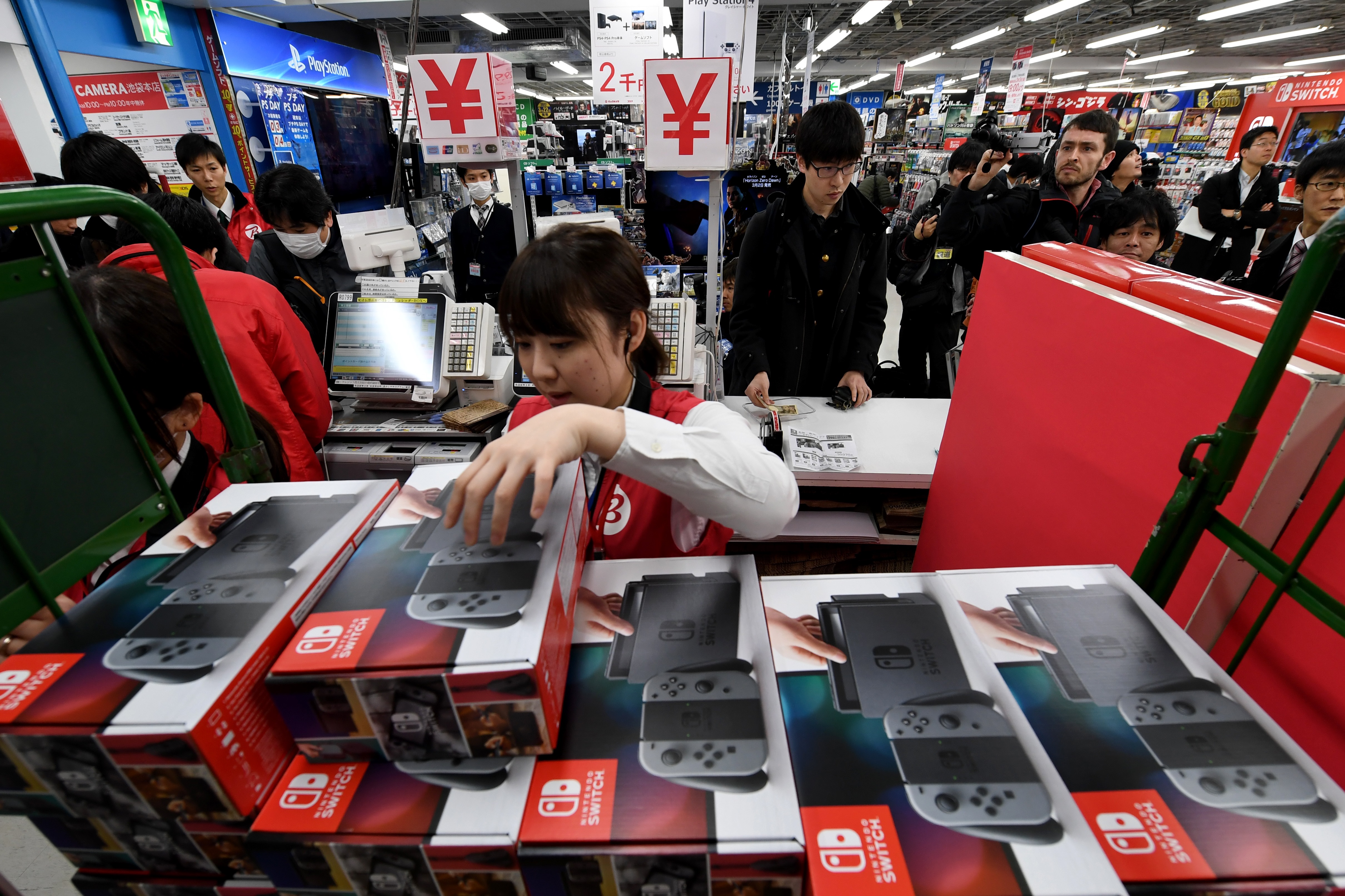 A shop clerk picks a package of a Nintendo Switch game console at cashier of a shop in Tokyo on March 3, 2017.  Nintendo's new game console, Switch is put on the Japanese market from March 3, 2017. / AFP PHOTO / TOSHIFUMI KITAMURA
